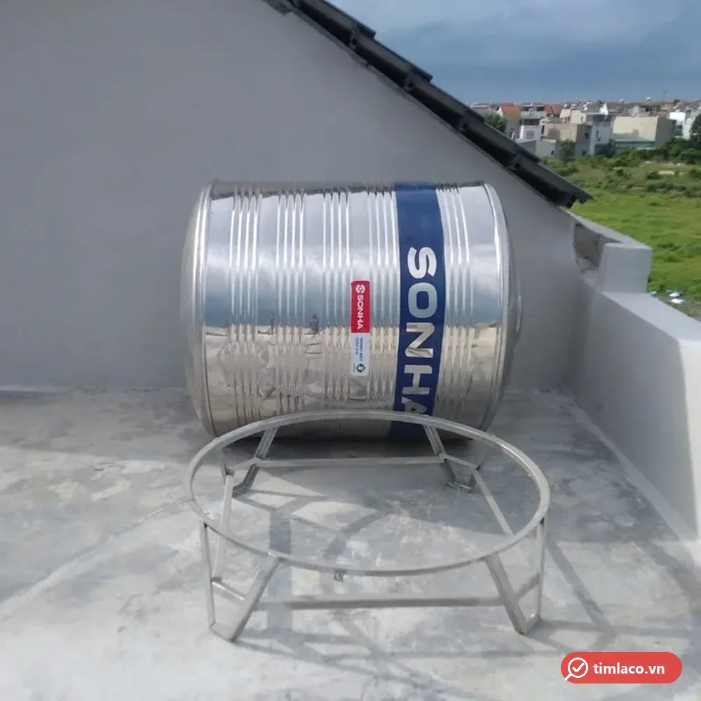 Bồn inox Sơn Hà dạng đứng đặt nằm cạnh chân đế vòng inox trước khi lắp, thân có tem Sơn Hà (ảnh minh hoạ dòng hàng)