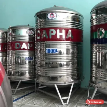 Bồn nước inox Dapha 1000 lít đứng, băng đỏ in chữ DAPHA và nhãn 1000L, đặt cạnh bồn 500 lít tại cửa hàng