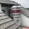 Bồn nước inox Dapha 2000 lít đứng lắp giữa hai mái ngói, băng đỏ chữ DAPHA và nhãn 2000L