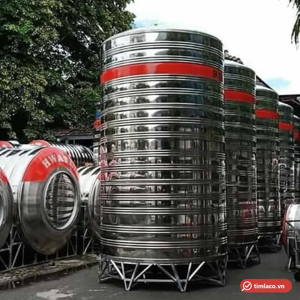 Bồn nước inox Hwata đứng cỡ lớn băng sơn đỏ trên chân inox tại bãi hàng, bên cạnh bồn ngang chữ HWATA (ảnh minh hoạ dòng hàng)