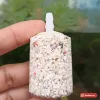 Cục sủi oxy sạn lớn hình trụ, hạt sạn trắng xen hạt đỏ, có đầu nối nhựa trắng, cầm trên tay
