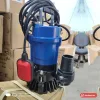 Máy bơm chìm nước thải APP thân xanh có phao điện màu đỏ và đầu nối ống xả, đặt trong kho (ảnh minh hoạ dòng hàng)